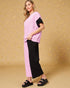 Woman wearing a pink top and black pants on a beige background