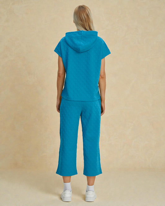 Person wearing a blue tracksuit against a beige background