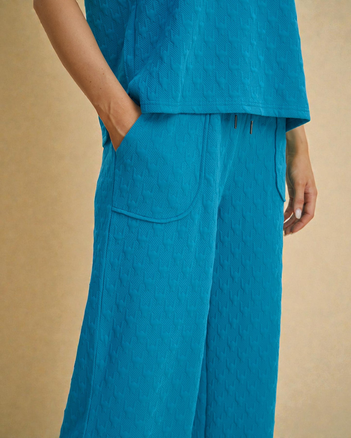 Person wearing a blue outfit with wide-leg pants on a beige background