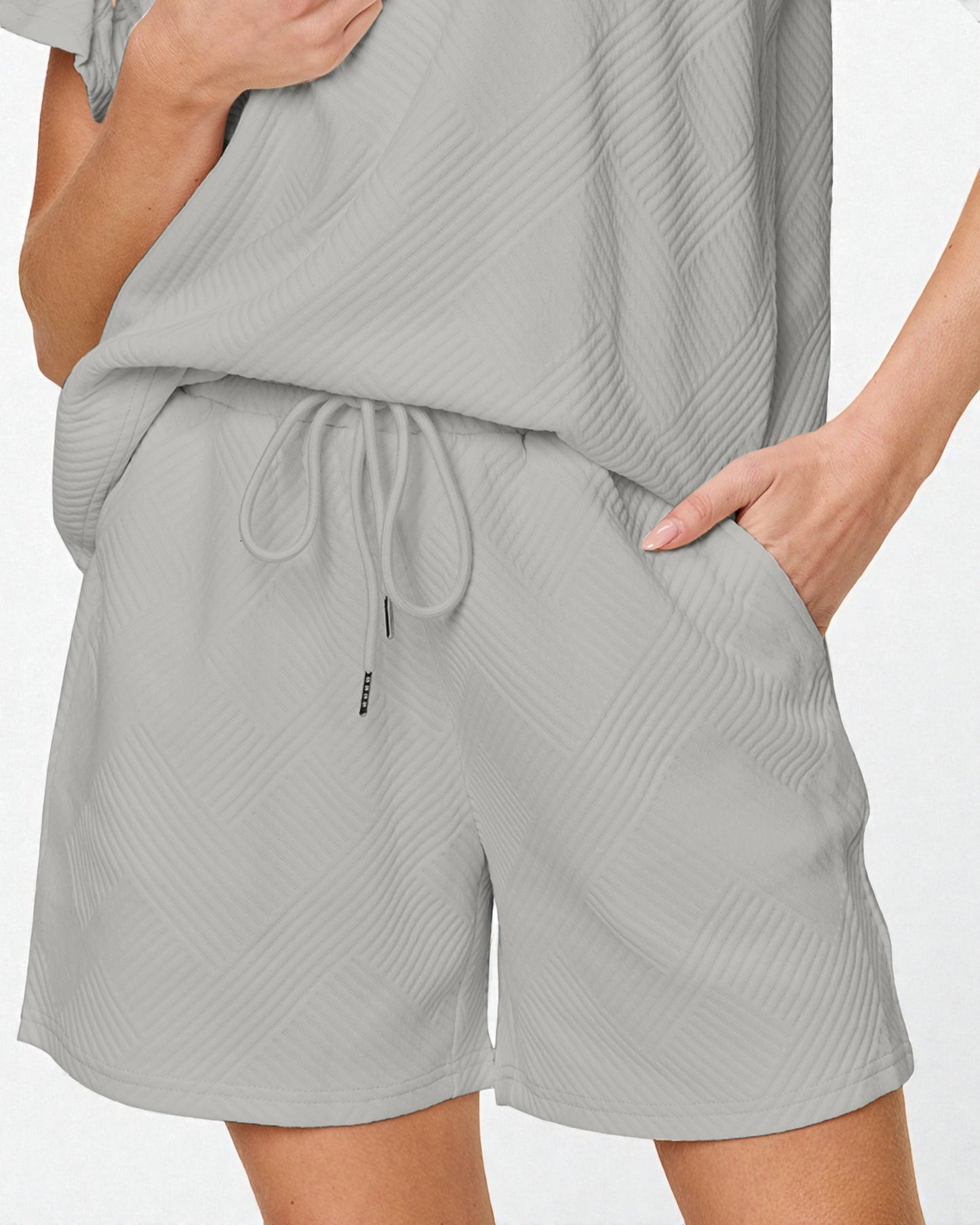 Person wearing a gray textured outfit with shorts and a top on a white background