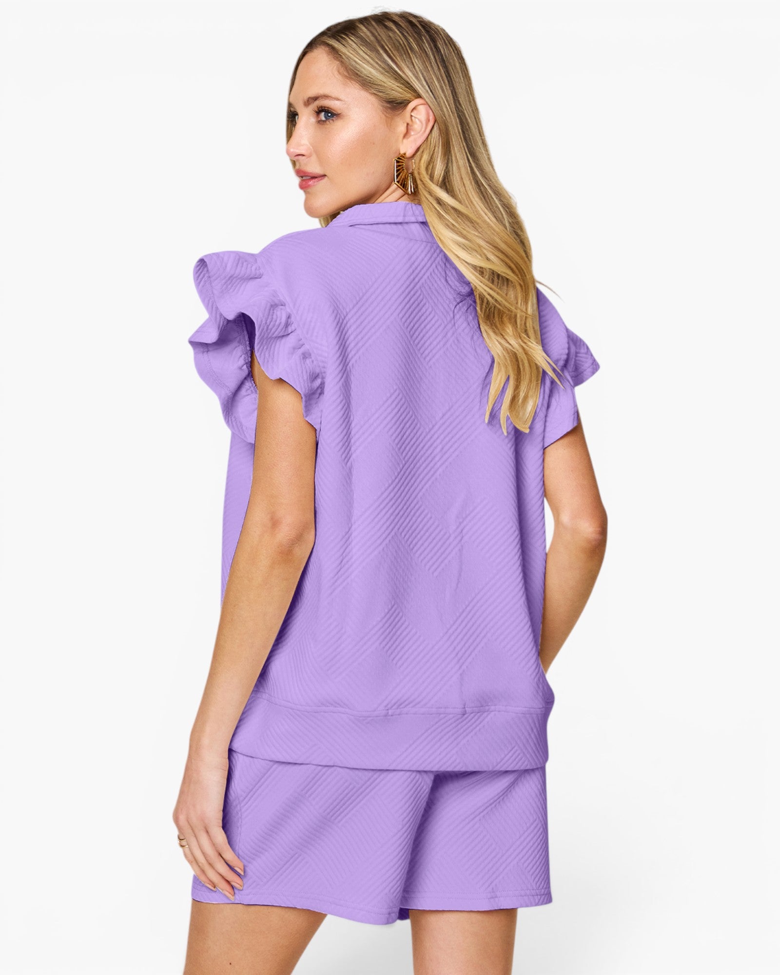 A woman shown from the back wearing a lavender purple textured two-piece lounge set consisting of a short-sleeve top with ruffled shoulder details and matching shorts, against a plain white studio background.