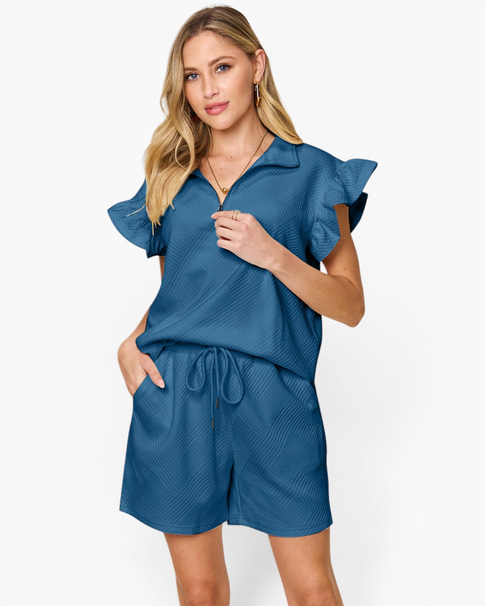 A woman modeling a blue short-sleeve romper with ruffled sleeves, a collar, and a drawstring waist, photographed against a plain light background.