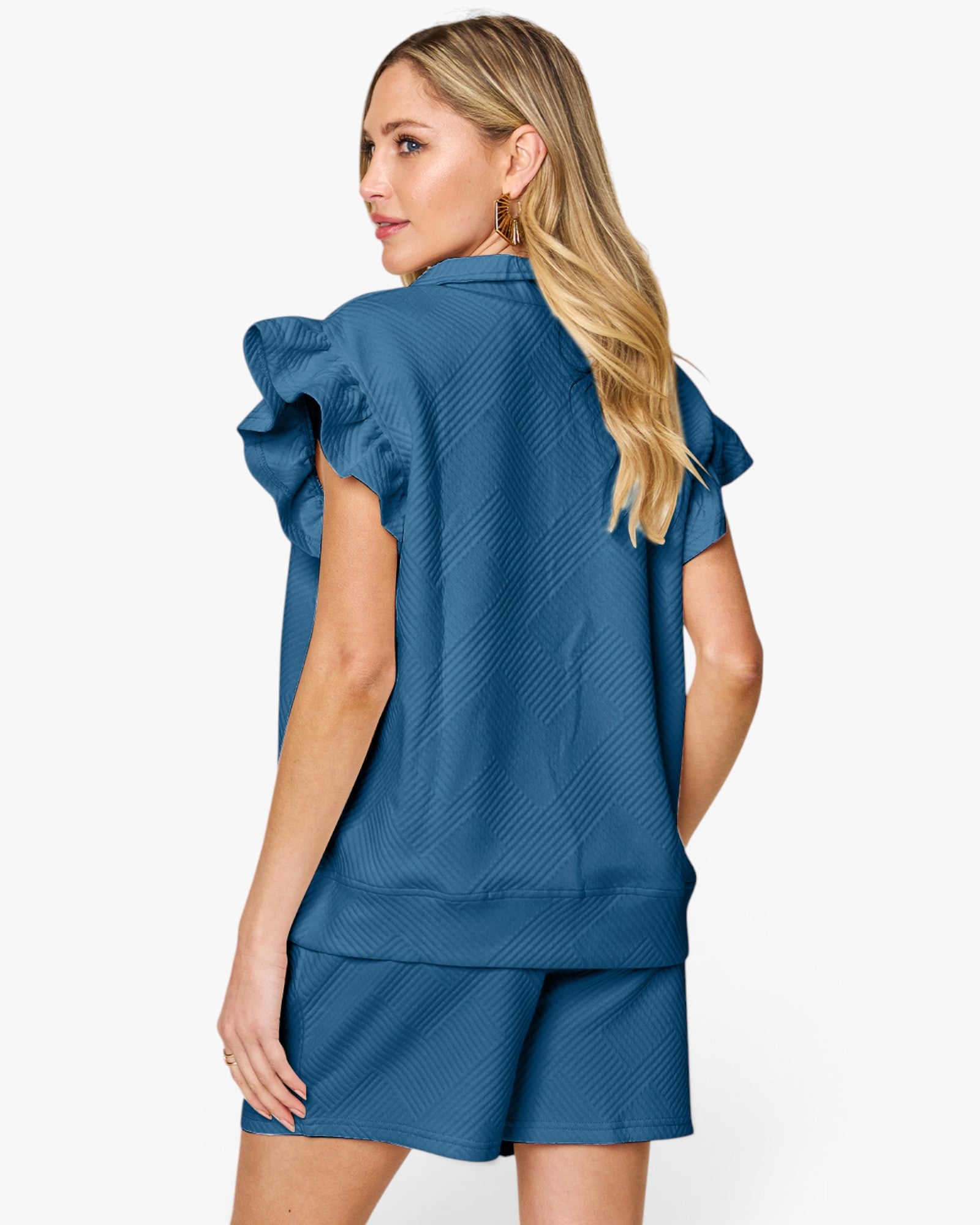 A woman shown from the back wearing a blue textured short-sleeve top with ruffled shoulder details and matching blue shorts against a plain white studio background.