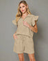 Woman wearing a beige outfit with ruffled sleeves on a beige background