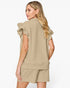 A woman shown from the back wearing a matching beige textured top and shorts set with ruffled short sleeves, against a plain white studio background.