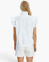 A woman shown from the back wearing a white sleeveless textured top with ruffled shoulders and matching white textured shorts against a plain white studio background.