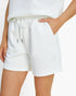 White textured waffle-knit shorts with a drawstring waist and side pockets, shown on a model against a plain white background.
