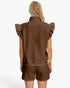 A woman shown from the back wearing a brown textured sleeveless top with ruffled shoulders and matching brown shorts against a plain white studio background.