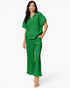 A woman modeling a matching bright green lounge set consisting of a short-sleeve half-zip top and wide-leg pants, photographed against a clean white studio background.