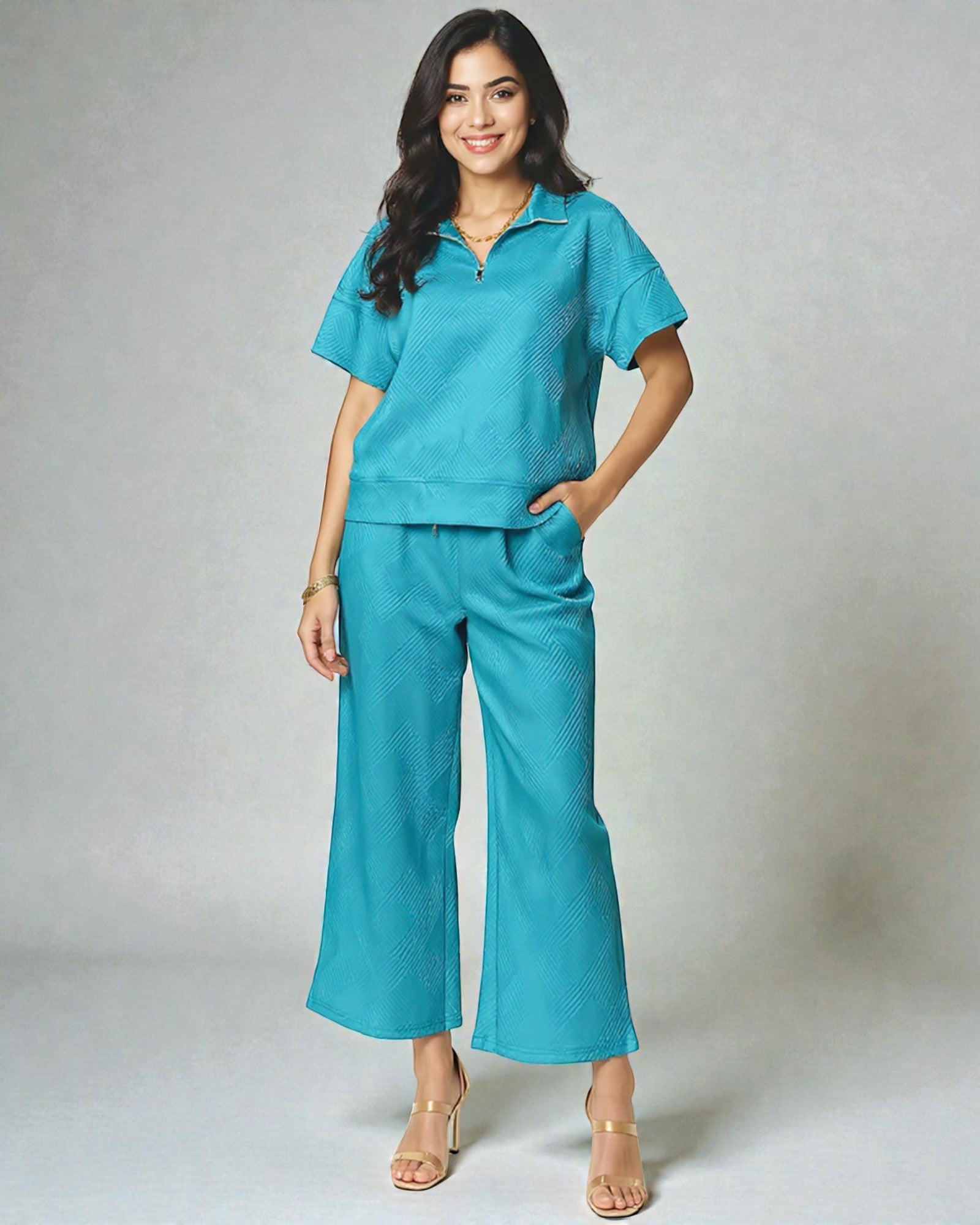 Woman wearing a teal outfit with wide-leg pants on a plain background