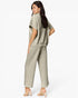 A woman modeling a light sage green two-piece set consisting of a short-sleeve cropped top and matching wide-leg cropped pants, shown from a three-quarters back view against a plain white studio background.