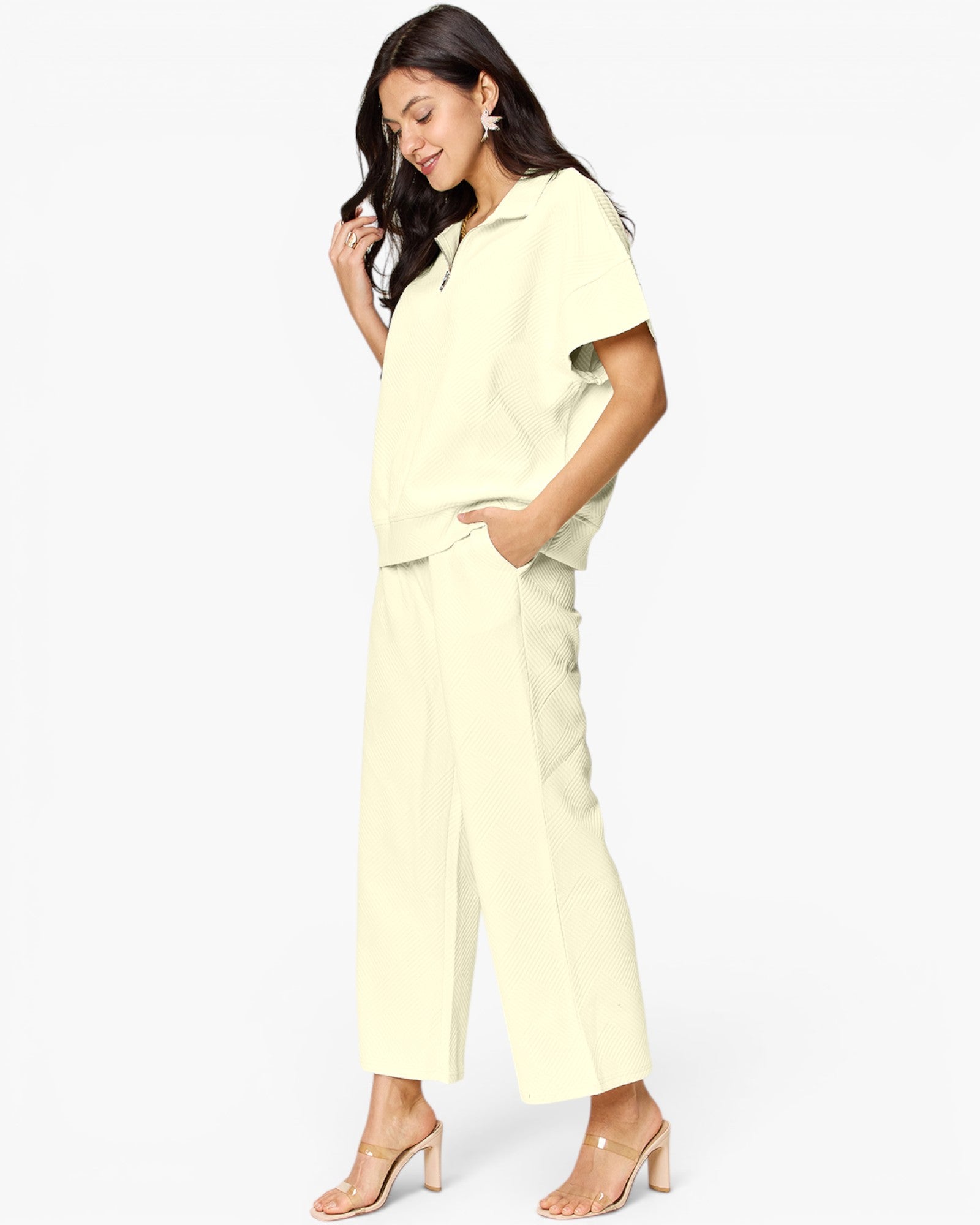 A woman modeling a pale yellow short-sleeve collared top and matching wide-leg cropped pants against a plain white studio background.