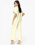 A woman modeling a pale yellow two-piece lounge set consisting of a short-sleeve top and matching wide-leg pants, shown from a three-quarters back view against a light gray studio background.