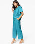 A woman modeling a matching teal short-sleeve collared top and wide-leg cropped pants set, paired with clear-strap heeled sandals, against a plain white studio background.