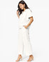 A woman modeling a white short-sleeve collared top and matching white wide-leg cropped pants, paired with clear strap heeled sandals, against a plain white studio background.