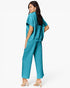 A woman modeling a matching turquoise blue two-piece set consisting of a short-sleeve cropped top and wide-leg cropped pants, shown from a three-quarters back view against a plain white studio background.
