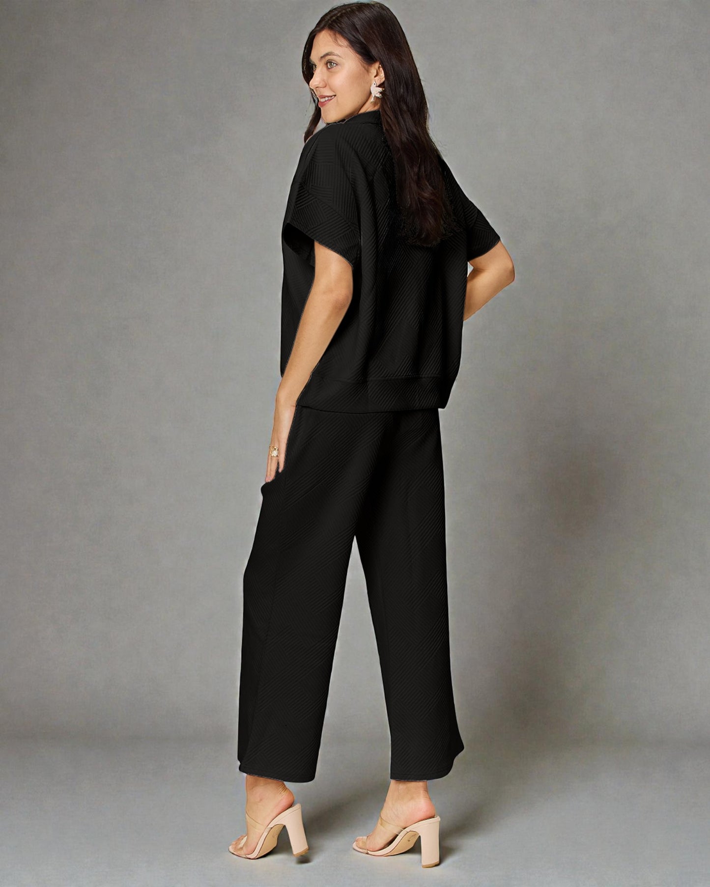 Woman wearing a black outfit against a gray background