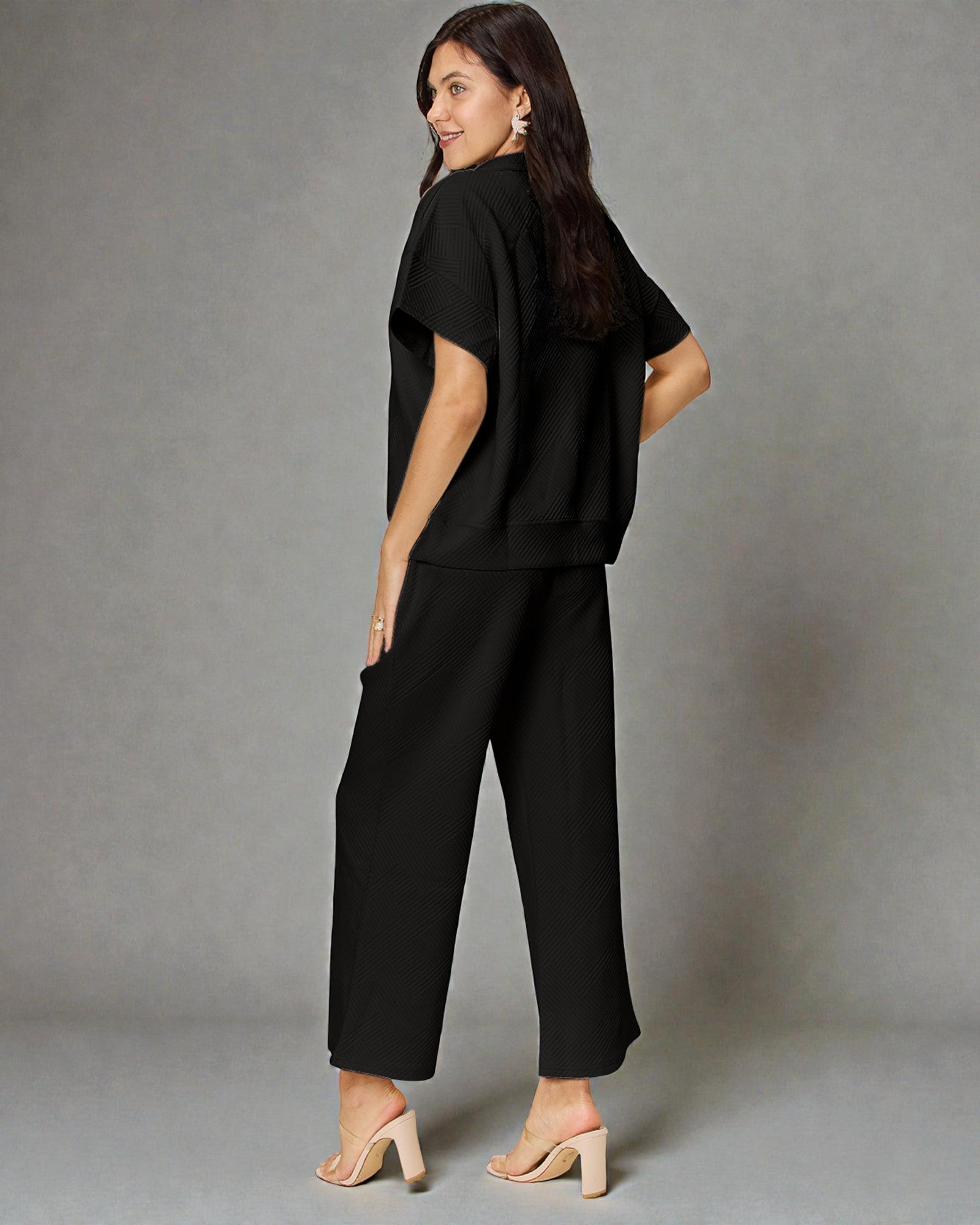 Woman wearing a black outfit against a gray background