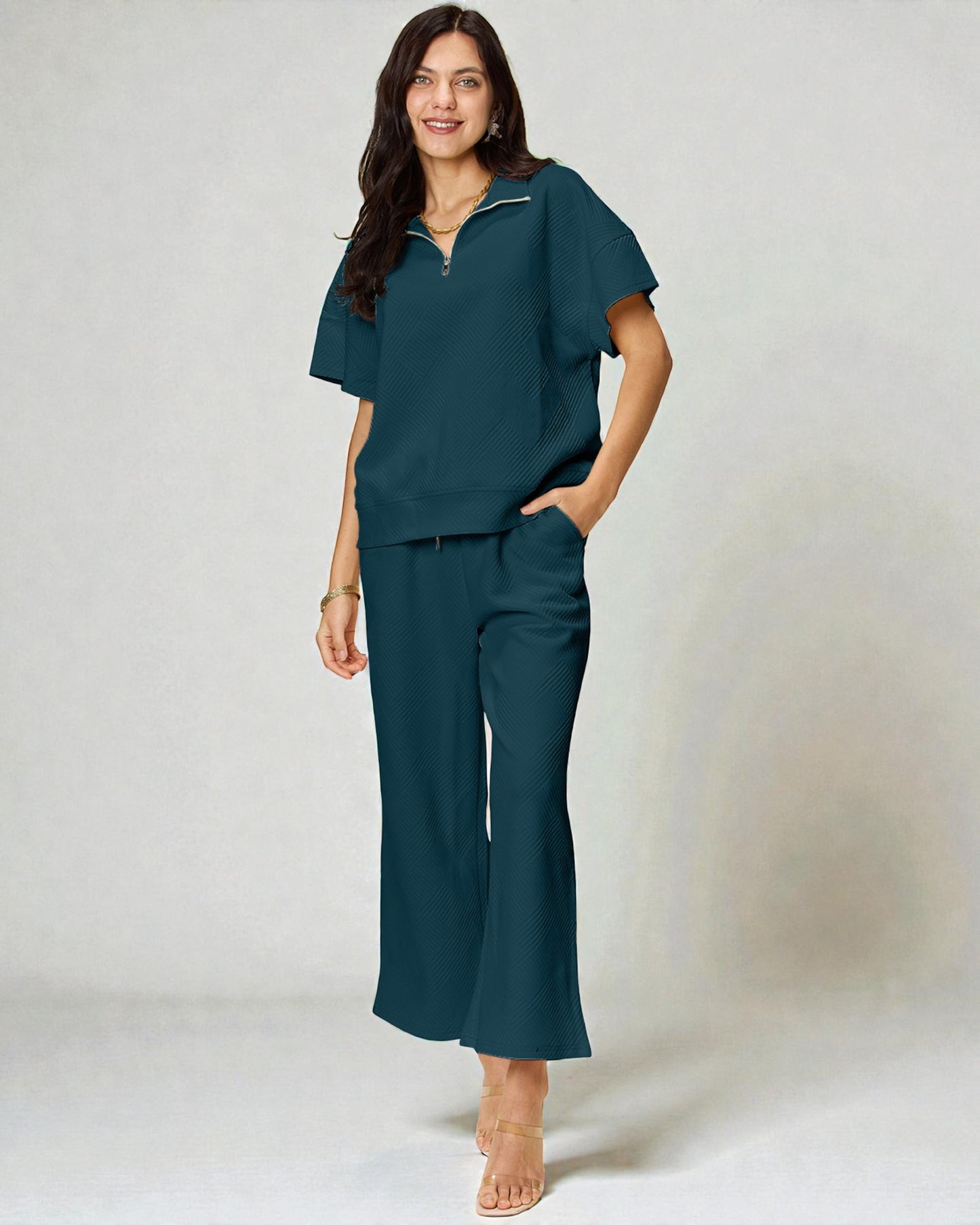 Woman wearing a teal outfit with wide-leg pants on a white background