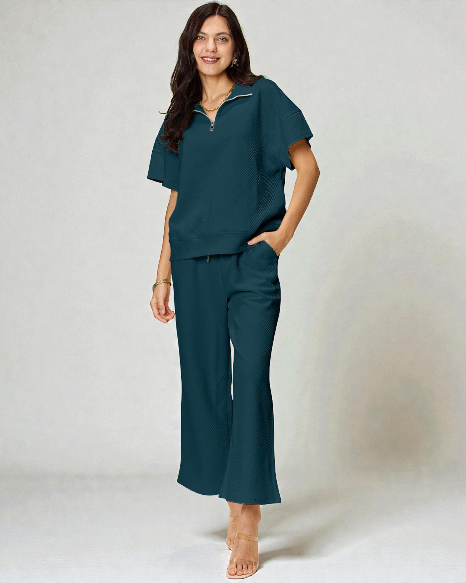 Woman wearing a teal outfit with wide-leg pants on a white background