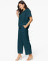 A woman modeling a dark teal two-piece set consisting of a short-sleeve collared top and matching wide-leg cropped pants, paired with nude heeled sandals against a plain white studio background.