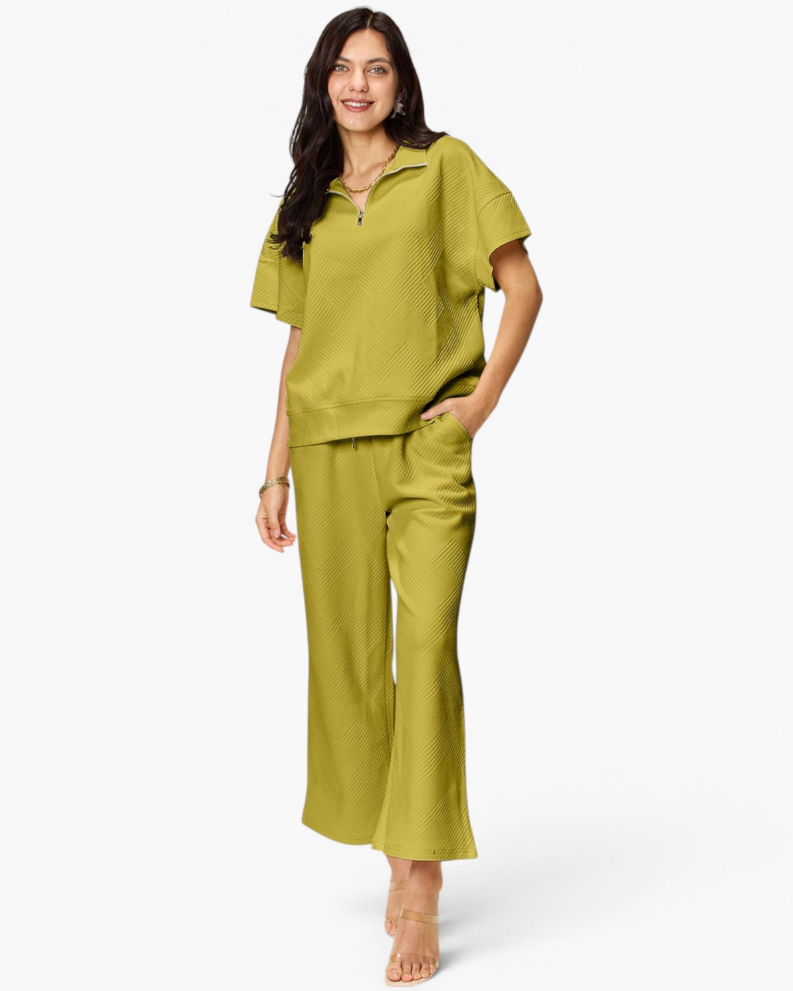 A woman modeling a matching olive green lounge set consisting of a short-sleeve half-zip top and wide-leg cropped pants, shot against a plain white studio background.