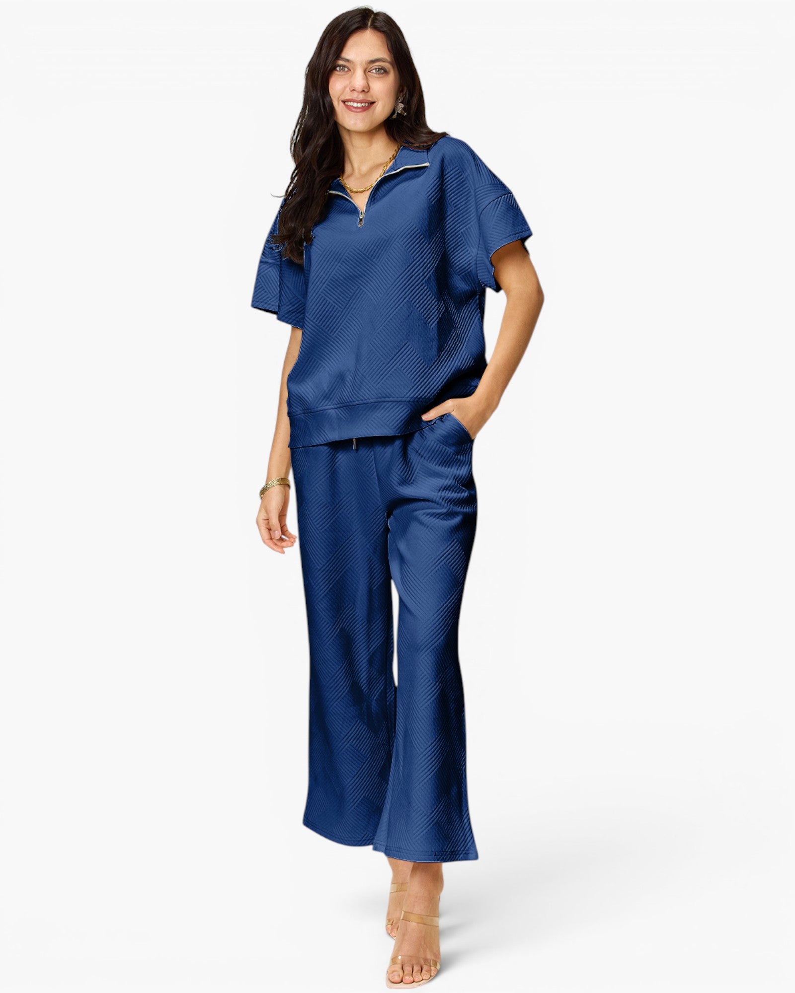 A woman modeling a matching two-piece lounge set in a rich royal blue color. The set includes a short-sleeve mock-neck top with a subtle textured pattern and matching wide-leg pants, photographed against a clean white studio background.