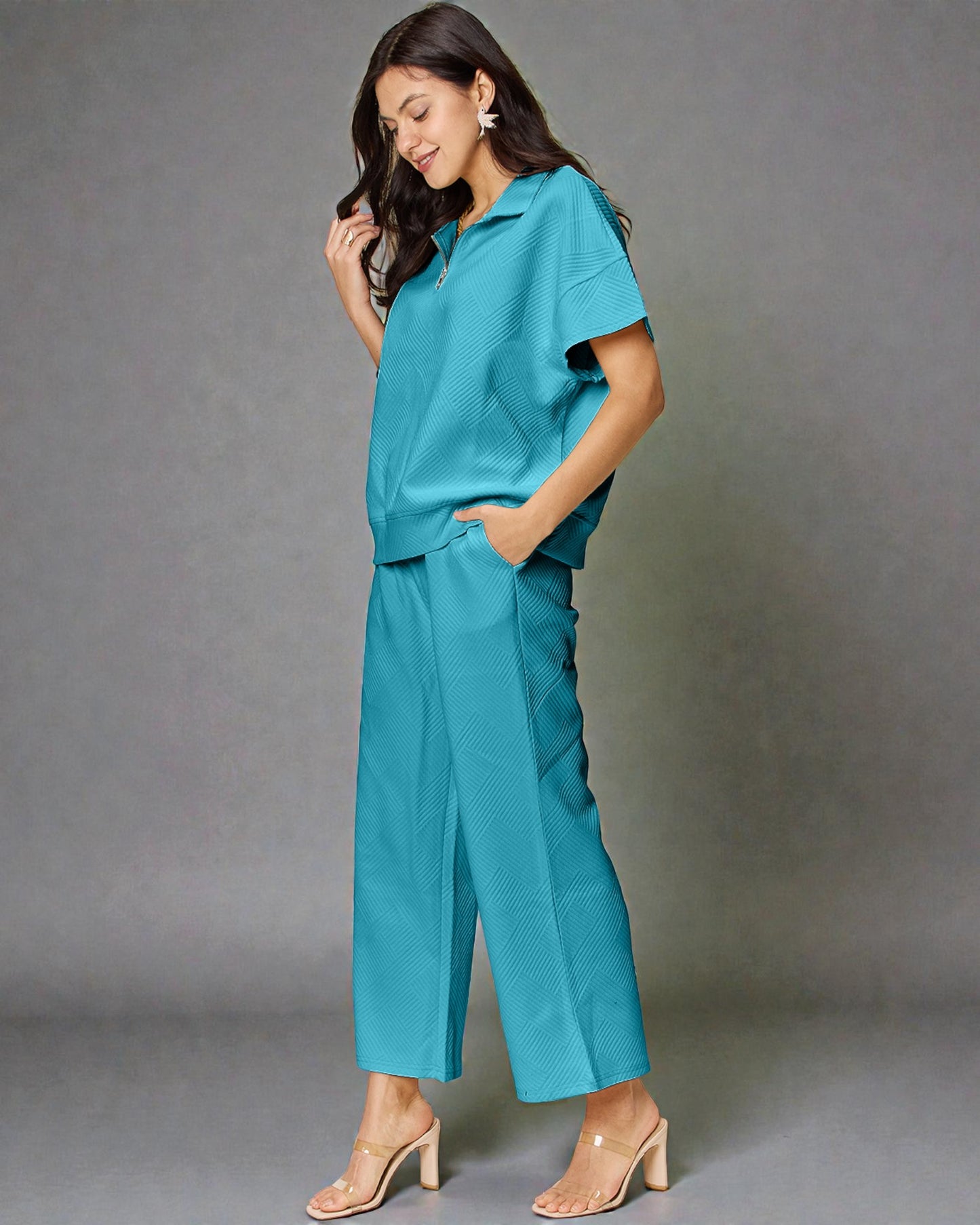 Woman wearing a teal outfit against a gray background