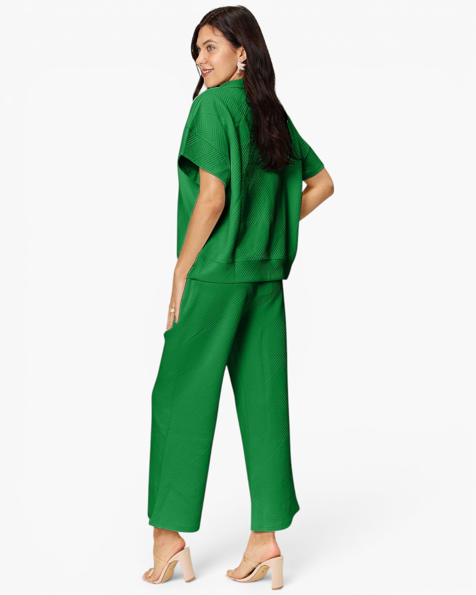 A woman modeling a bright green two-piece lounge set consisting of a short-sleeve cropped sweatshirt and matching wide-leg pants, shown from a three-quarters back view against a plain white studio background.