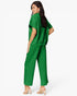 A woman modeling a bright green two-piece lounge set consisting of a short-sleeve cropped sweatshirt and matching wide-leg pants, shown from a three-quarters back view against a plain white studio background.