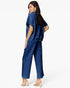 A woman modeling a matching navy blue two-piece set consisting of a short-sleeve cropped top and wide-leg cropped pants, shown from a three-quarters back view against a plain white studio background.