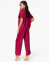 A woman modeling a matching magenta two-piece lounge set consisting of a short-sleeve top and wide-leg cropped pants, shown from a three-quarters back view against a plain white studio background.