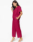 A woman modeling a matching magenta two-piece set consisting of a short-sleeve collared top and wide-leg cropped pants, paired with clear-strap heeled sandals against a plain white background.