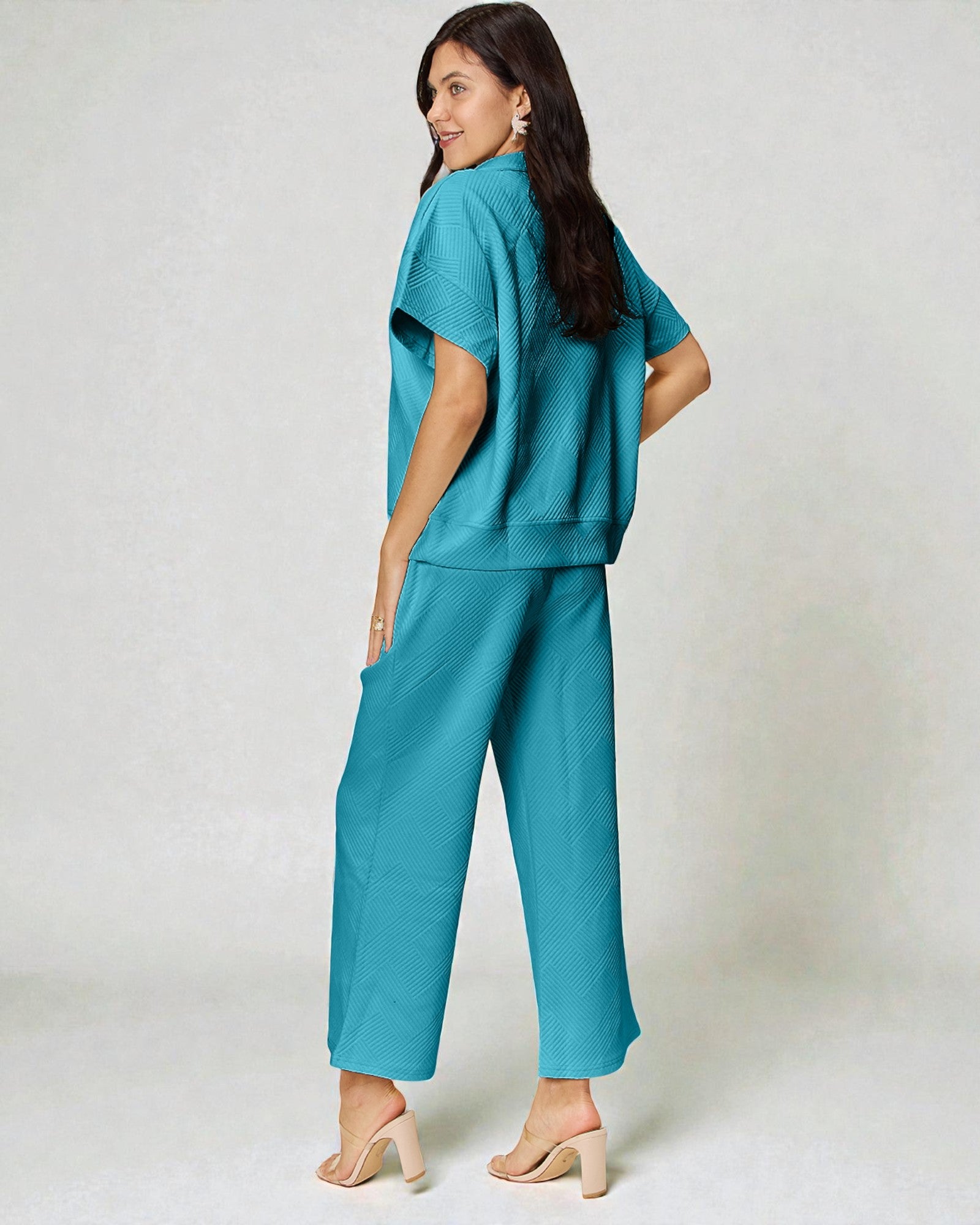 Woman wearing a teal outfit on a plain background