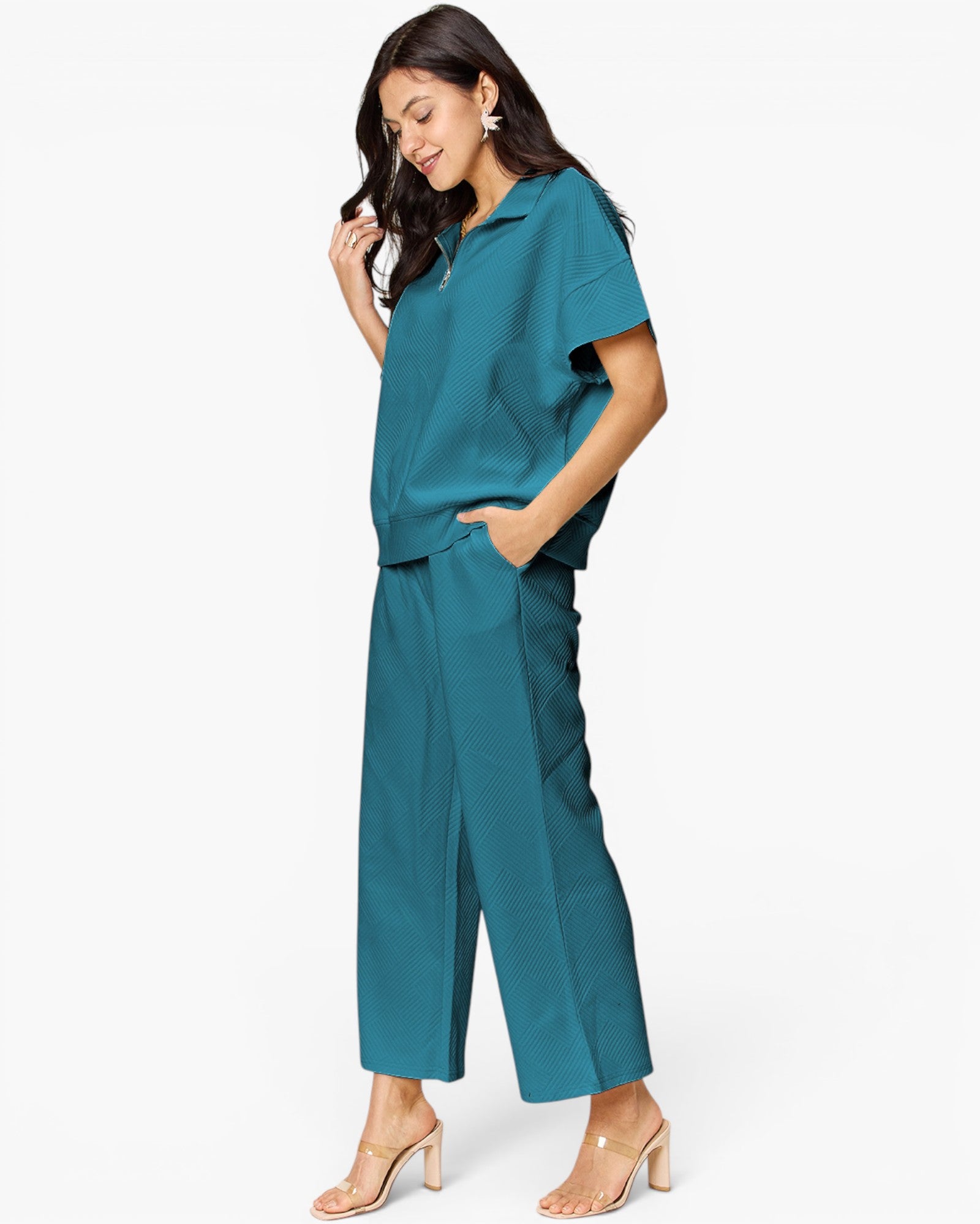 A woman modeling a teal short-sleeve collared top and matching wide-leg cropped pants against a clean white studio background.