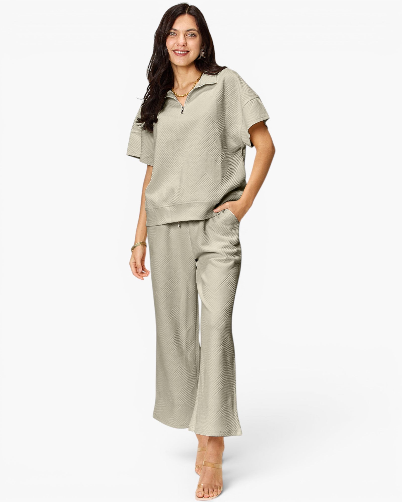 A woman modeling a matching two-piece lounge set consisting of a short-sleeve collared top and wide-leg cropped pants in a light sage green color, set against a plain white studio background.