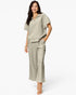 A woman modeling a matching two-piece lounge set consisting of a short-sleeve collared top and wide-leg cropped pants in a light sage green color, set against a plain white studio background.