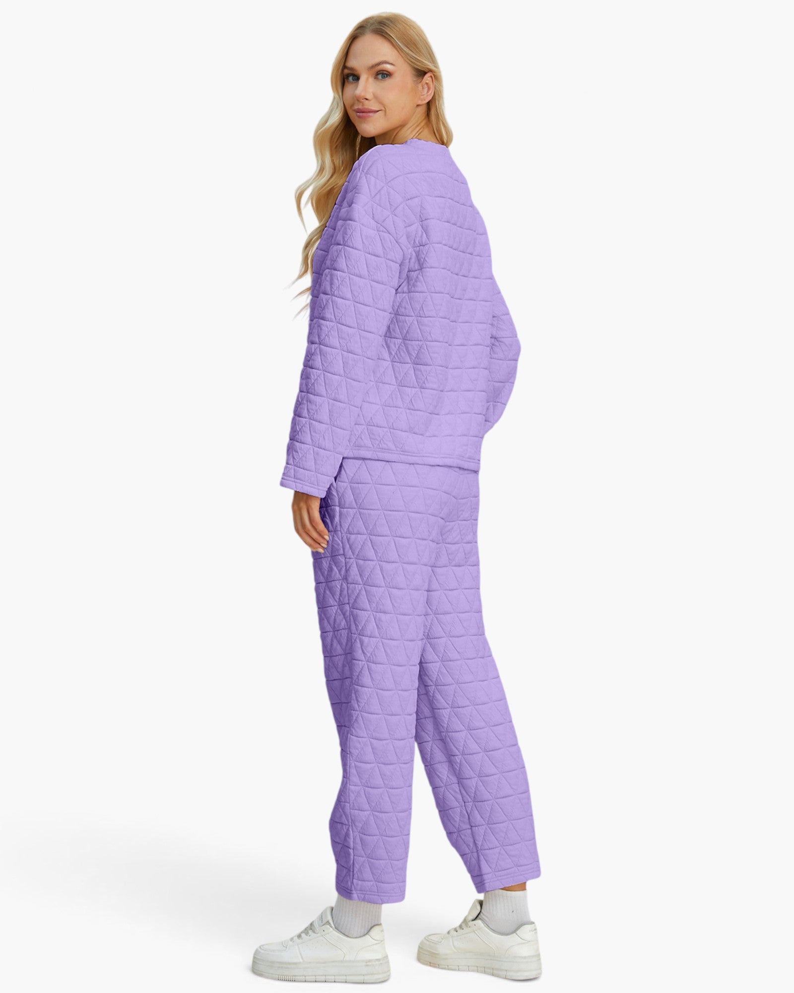 A woman modeling a light purple quilted two-piece pajama set, featuring a long-sleeve top and matching pants, shown from a rear three-quarter angle against a plain white studio background.