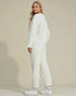 Woman wearing a white quilted outfit against a beige background