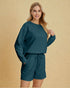 Woman wearing a teal outfit with a matching top and shorts on a beige background