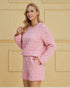 Woman wearing a pink quilted outfit against a beige wall