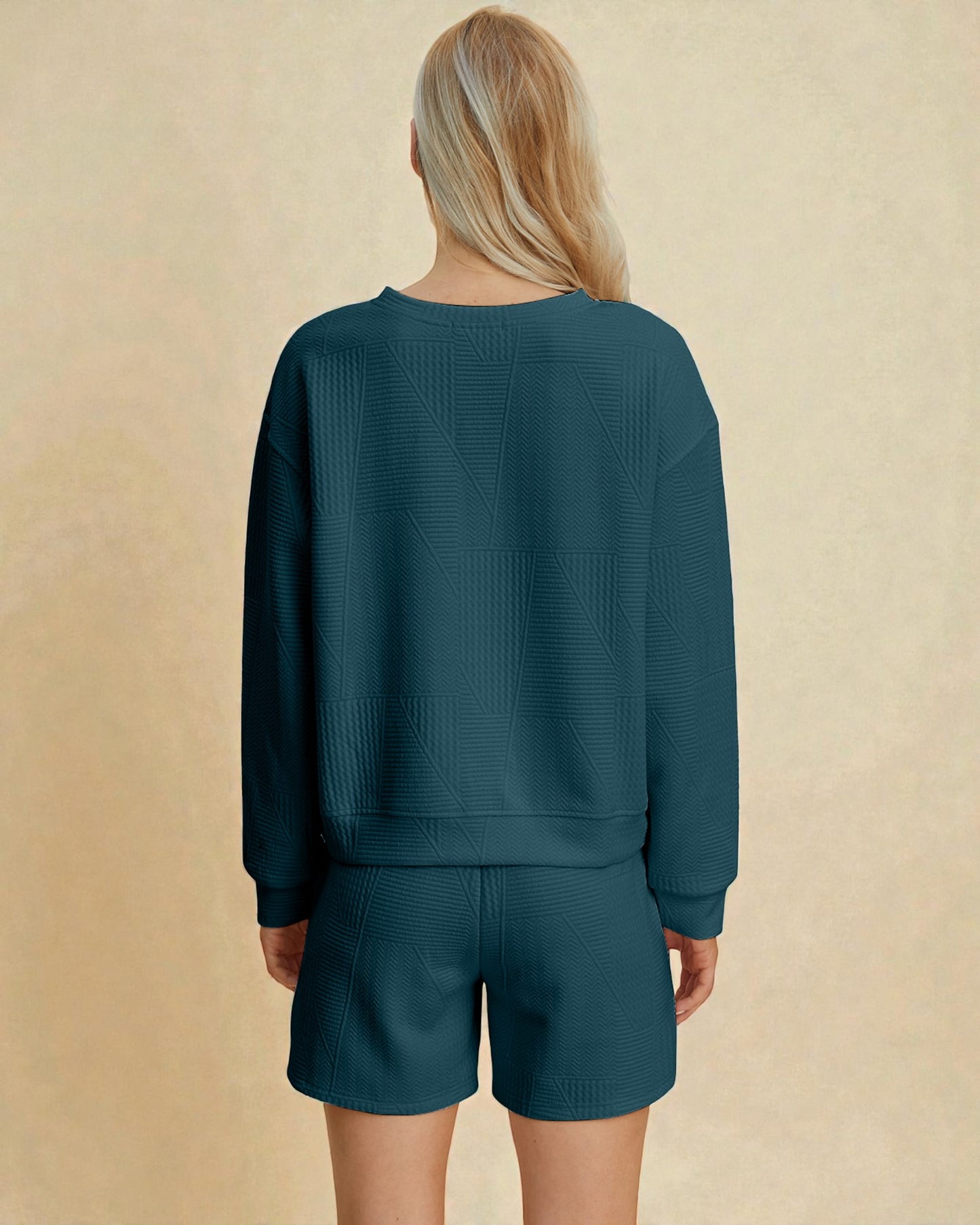 Person wearing a teal sweater and shorts set on a beige background