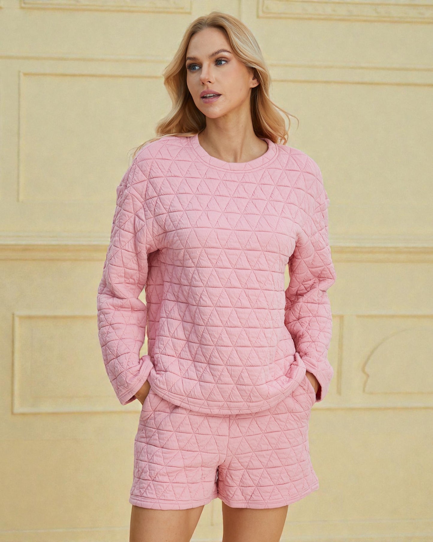 Woman wearing a pink quilted outfit against a yellow wall