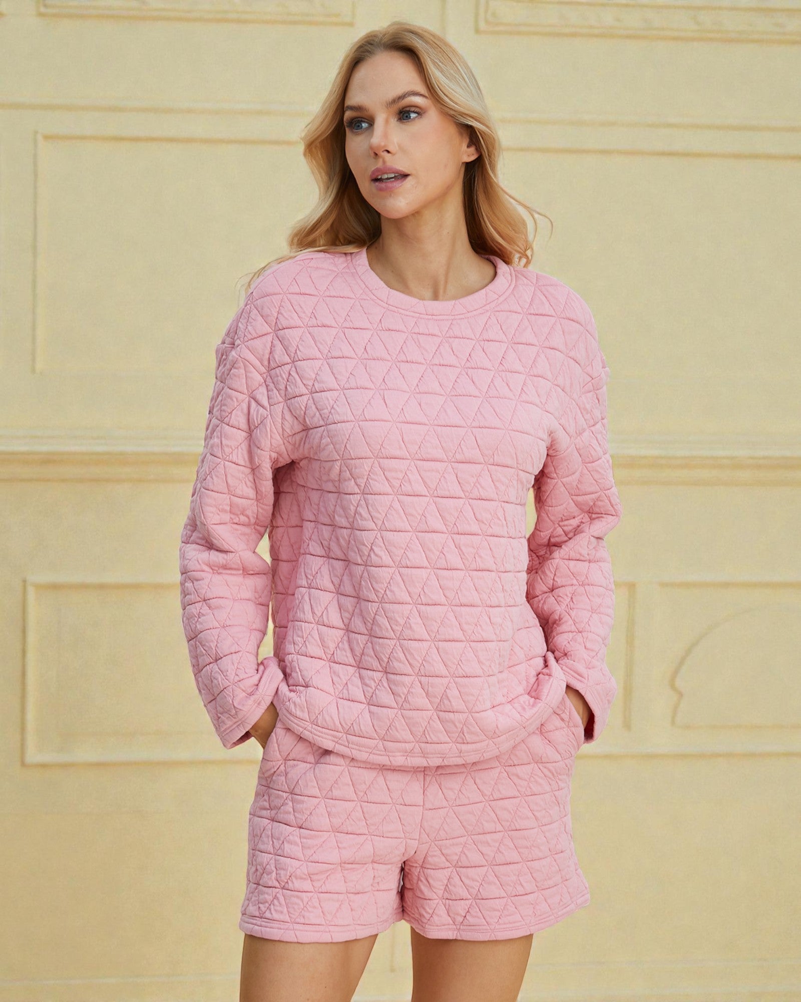 Woman wearing a pink quilted outfit against a yellow wall