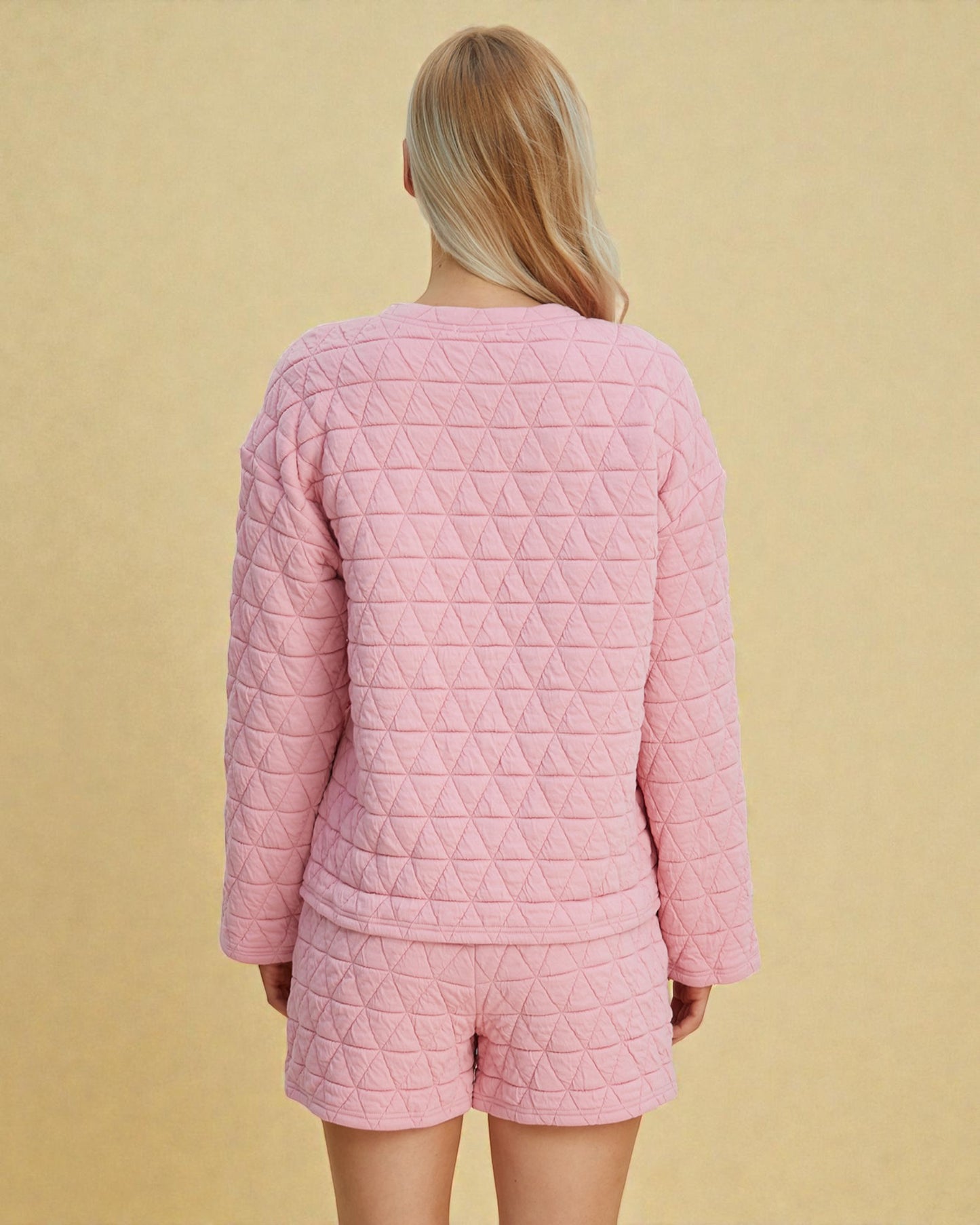 Person wearing a pink quilted pajama set against a beige background