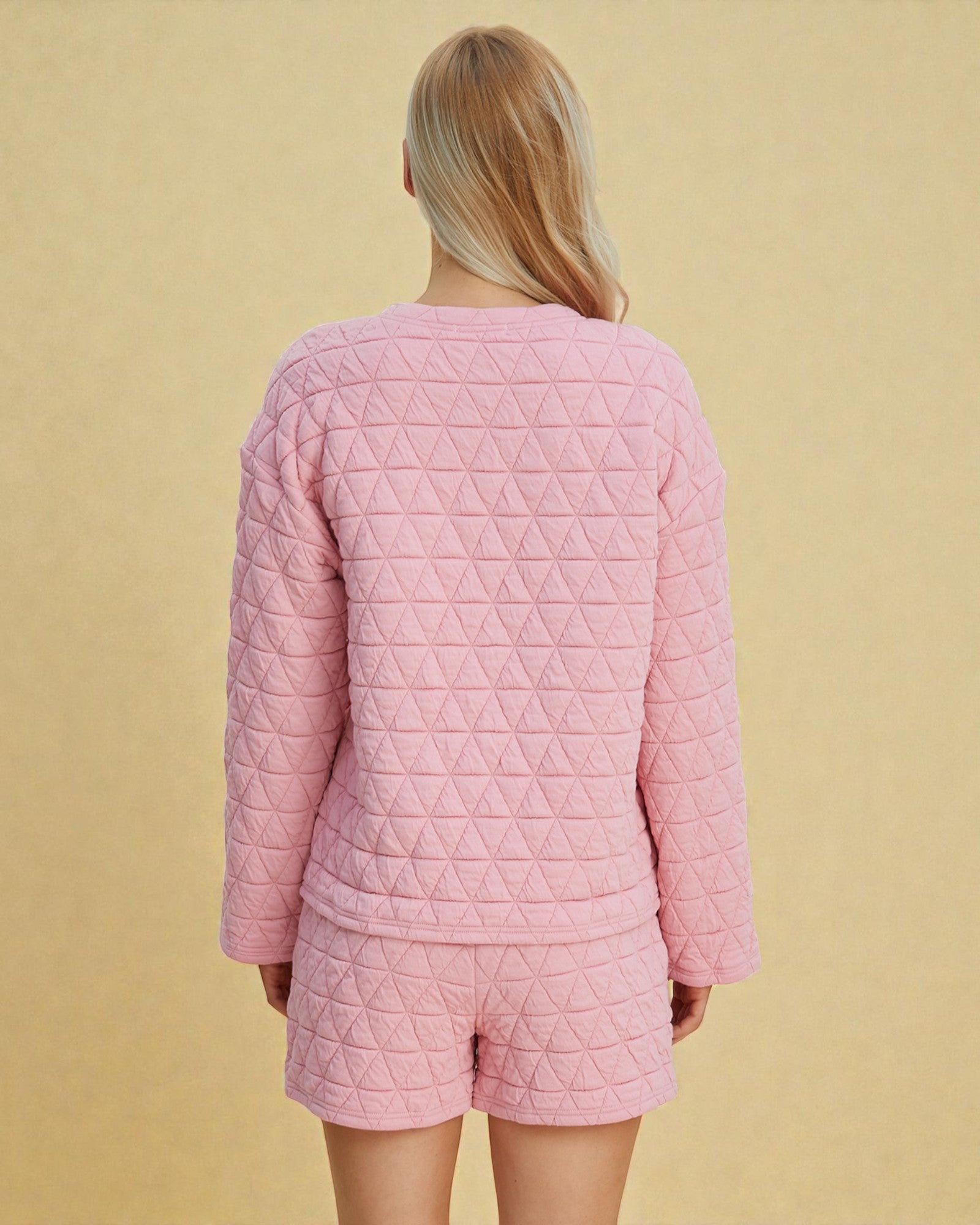 Person wearing a pink quilted pajama set against a beige background