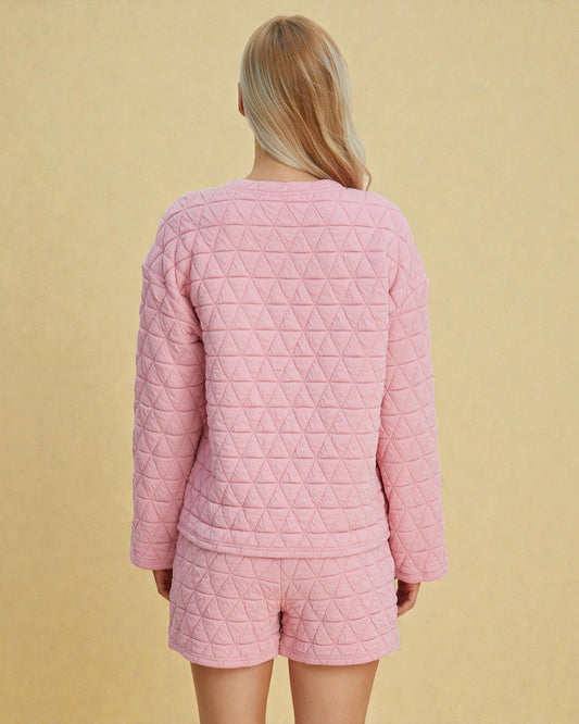 Person wearing a pink quilted pajama set against a beige background