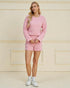 Woman wearing a pink quilted outfit against a beige wall