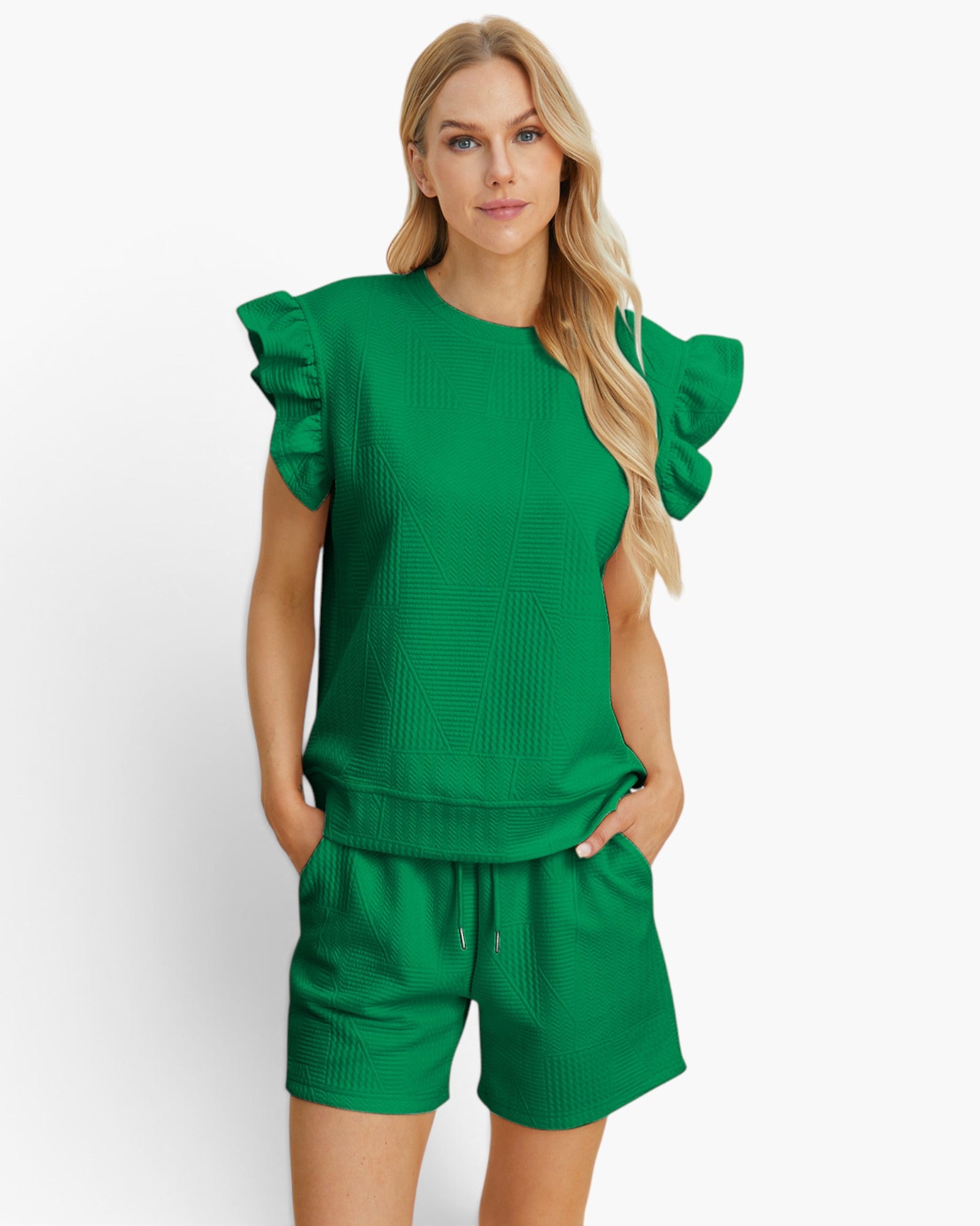 A woman modeling a bright green two-piece lounge set consisting of a textured short-sleeve top with ruffled sleeves and matching drawstring shorts, set against a plain white studio background.