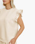 A close-up of a model wearing a cream-colored sleeveless top with textured vertical panels and ruffled cap sleeves, set against a plain white background.